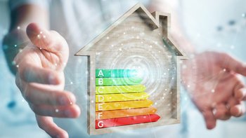 Energieeffizienz im Fokus: Ein Haus mit Bewertungsskala Zwei Hände die ein Energieeffizienzklasse mit einem Haus umrandet halten