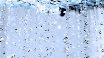 Faszinierende Tropfen, die im Licht funkeln Wassertropfen fallen in einer sanften Bewegung, während sie im Licht funkeln und eine ruhige Atmosphäre schaffen.