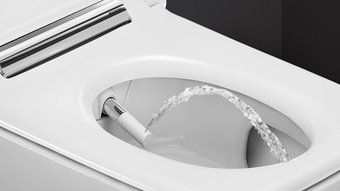 Moderne Toilette mit innovativer Wasserfunktion Ein modernes Bidet mit einem Wasserstrahl, der aus der Düse in die Toilettenschüssel spritzt, auf einem weißen Hintergrund.