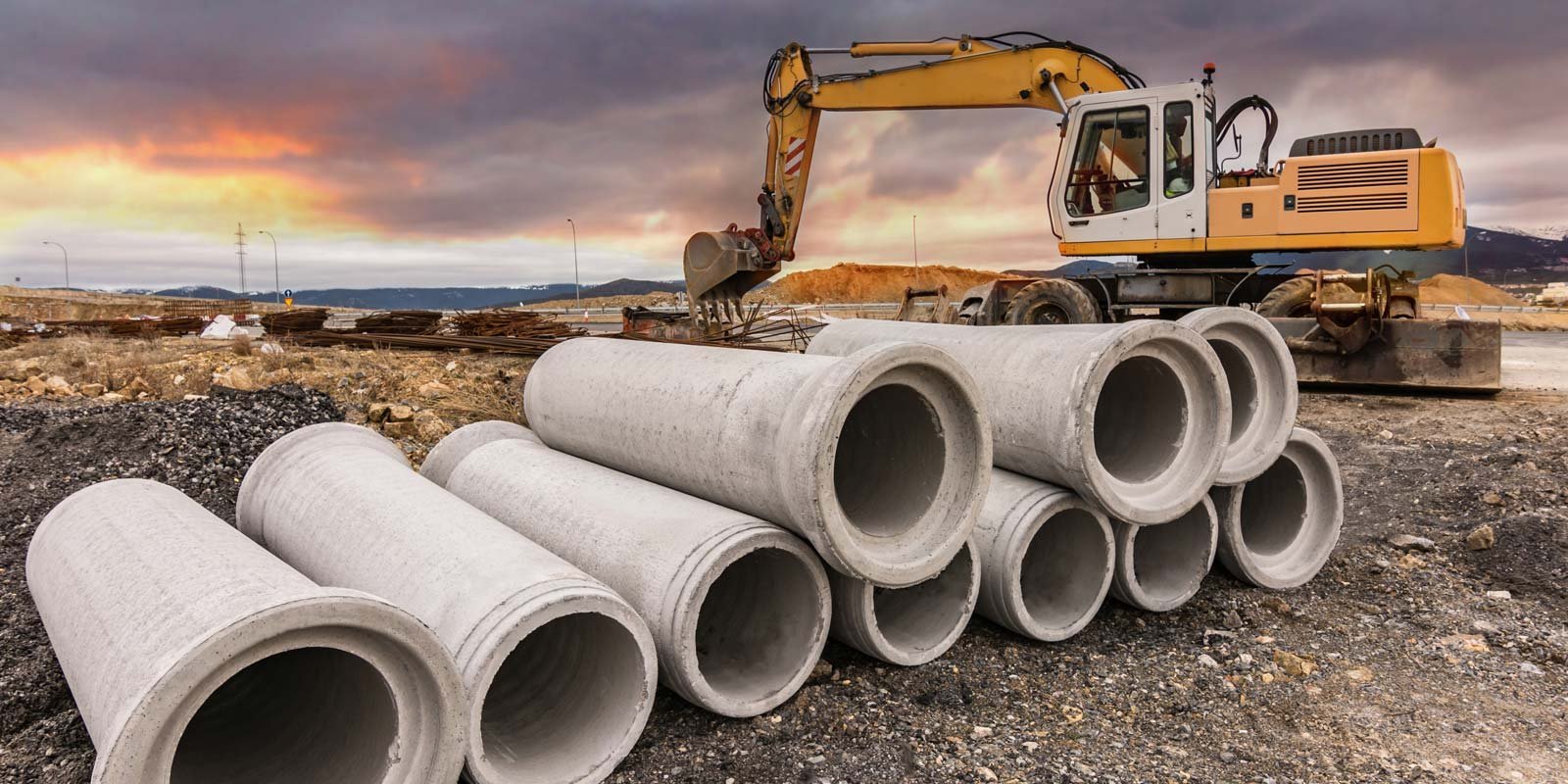 Eine Baustelle mit Kanalrohren und einem Bagger