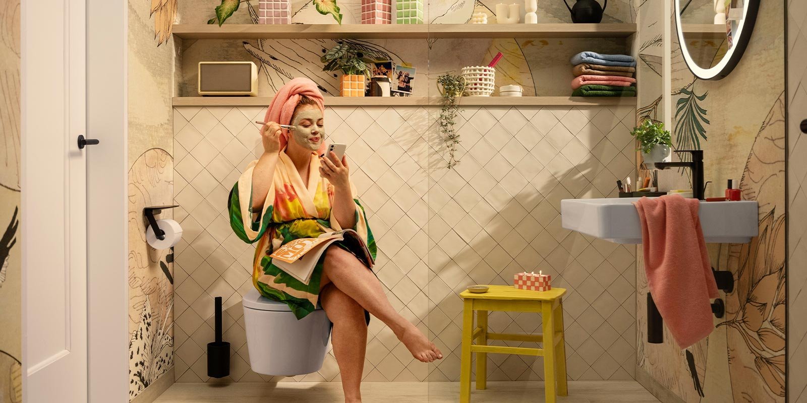 Entspannung im Badezimmer: Gesichtsmasken und Selbstpflege Eine Frau mit einer Gesichtsmaske sitzt entspannt auf der Toilette und schaut auf ihr Handy, während sie ein Magazin hält.