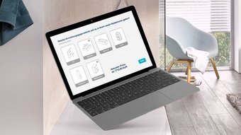 Moderne Badezimmergestaltung mit interaktivem Laptop-Design Ein Laptop schwebt über einem Badezimmerwaschtisch, während eine Auswahl an Badezimmermöbeln auf dem Bildschirm angezeigt wird.