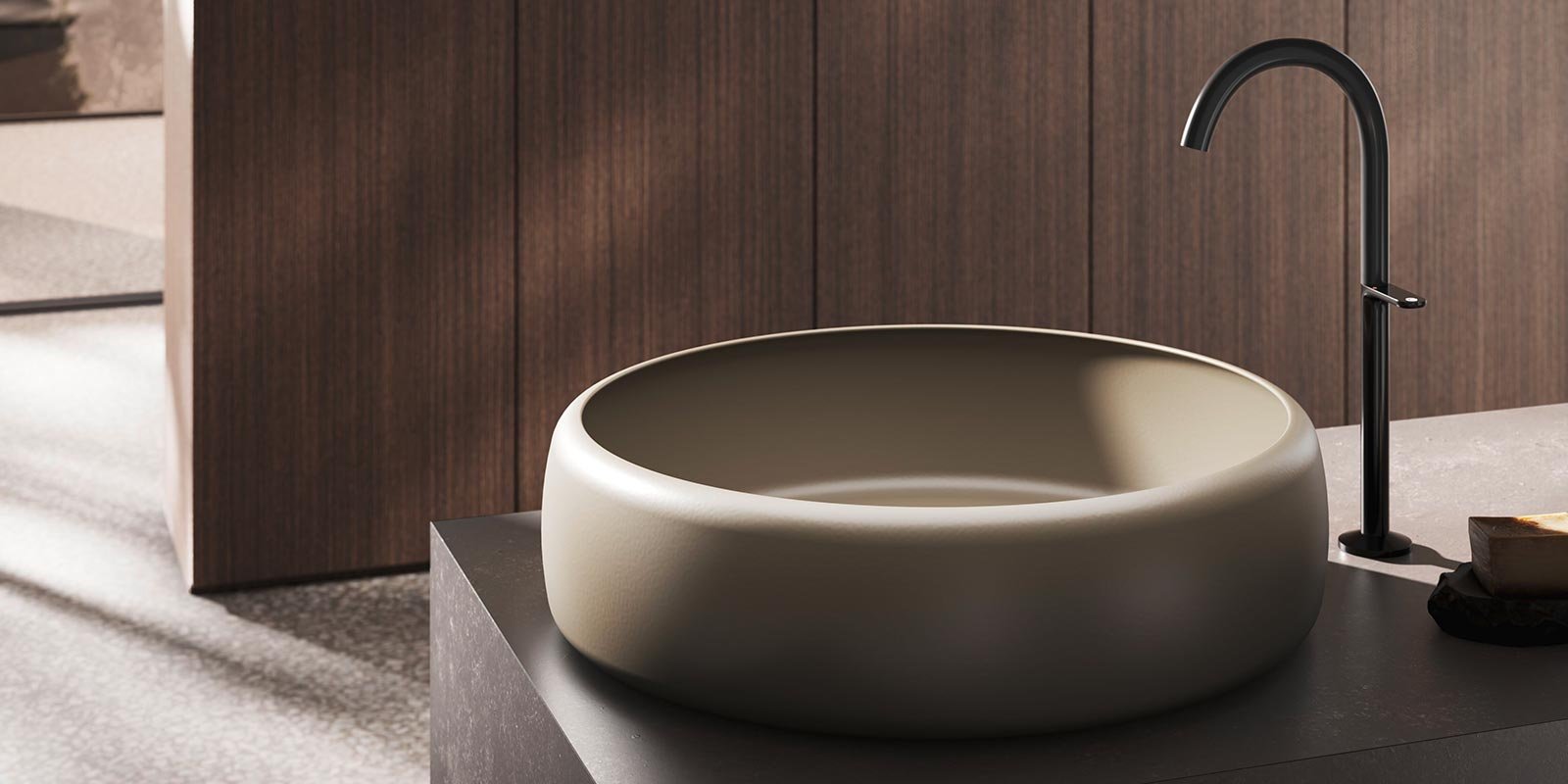 Ein elegantes, rundes Waschbecken aus hellem Material steht auf einer dunklen Arbeitsplatte in einem modernen Raum.